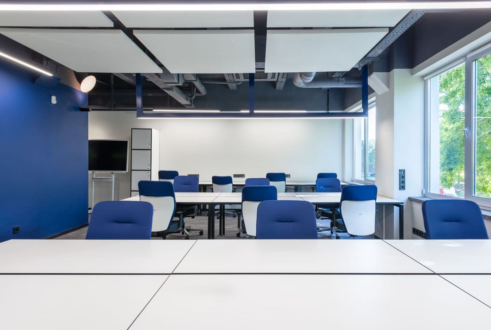 Clean modern meeting room with white tables and blue chairs