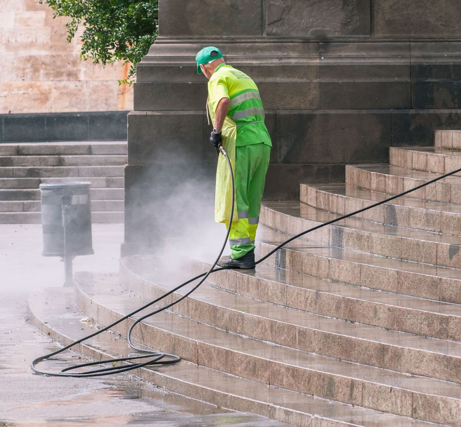 Worker pressure washing outdoor stone steps